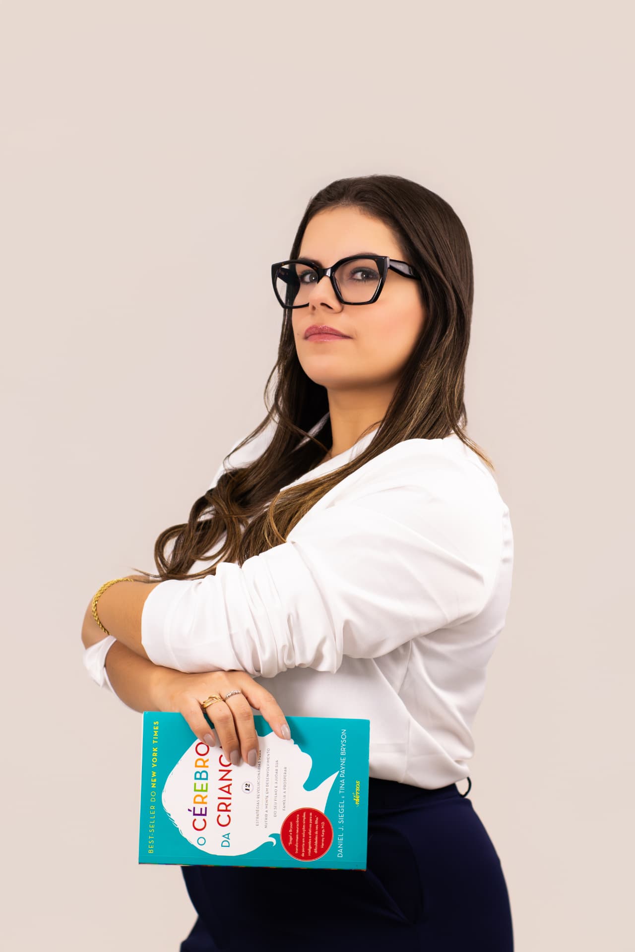Carina segurando o livro O Cérebro da Criança em seu consultório